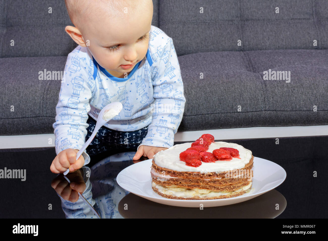 Primo compleanno di un ragazzino. Little Boy di mangiare la torta di compleanno con un cucchiaio, buon compleanno. Bambino a tavola con torta. Foto Stock