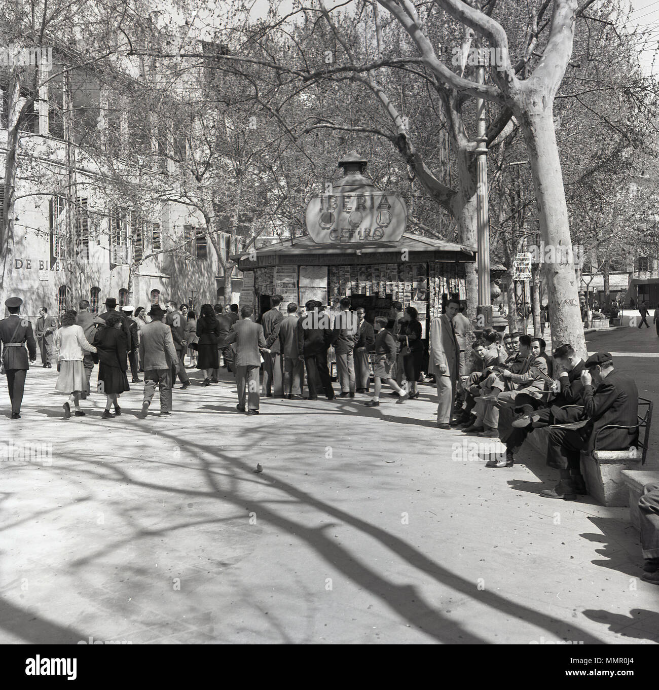 Degli anni Cinquanta, le persone si radunano attorno ad una edicola di giornali o riviste kiosk nella palma, la capitale di Maiorca, Spagna. Foto Stock