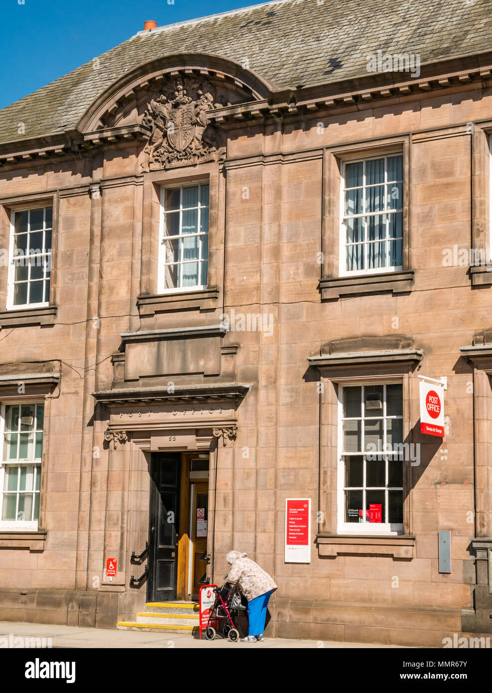 Haddington Post Office frontage, edificio storico, Court Street, East Lothian, Scozia disabilitato vecchia donna con mobilità rollator supporto su ruote Foto Stock