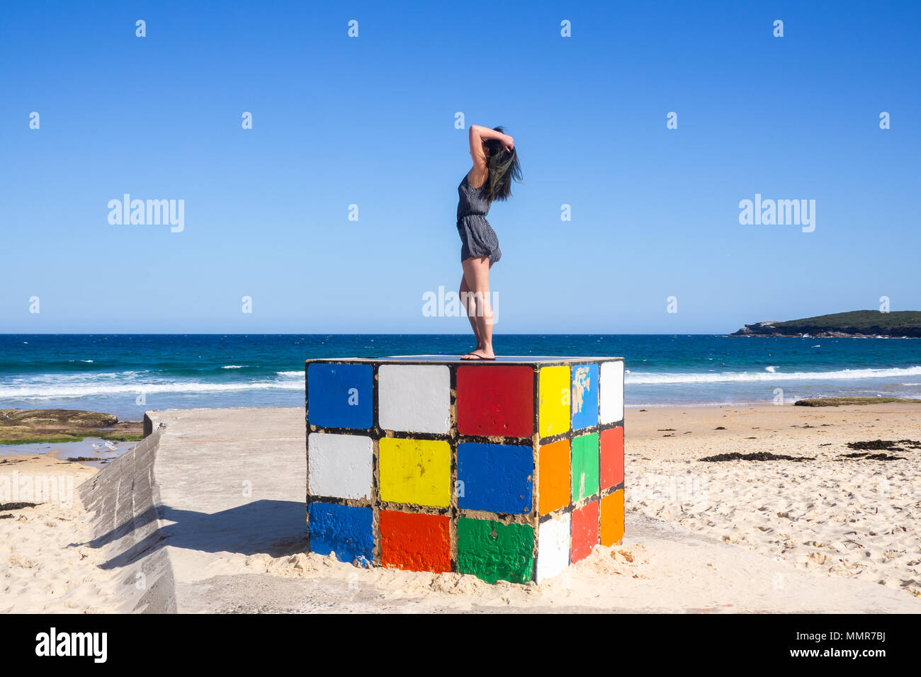 Giovane donna sorge su un gigantesco cubo di Rubik a Maroubra Beach, Sydney, Australia Foto Stock