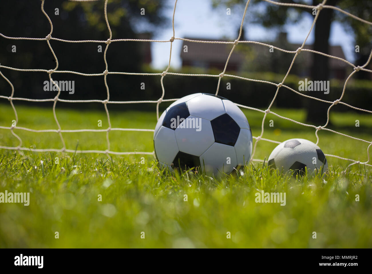 Due palloni da calcio in rete: uno più piccolo e uno più grande Foto Stock