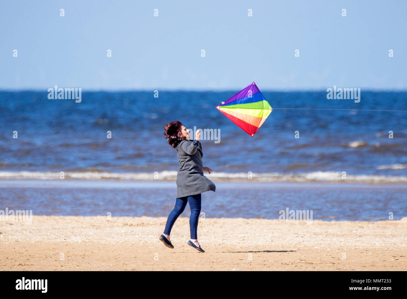 Southport, Merseyside. 13 maggio 2018. Regno Unito Meteo. Una donna ha il grande divertimento cerca di catturare il suo kite sulle sabbie dorate della spiaggia di Southport nel Merseyside. Credito: Cernan Elias/Alamy Live News Foto Stock