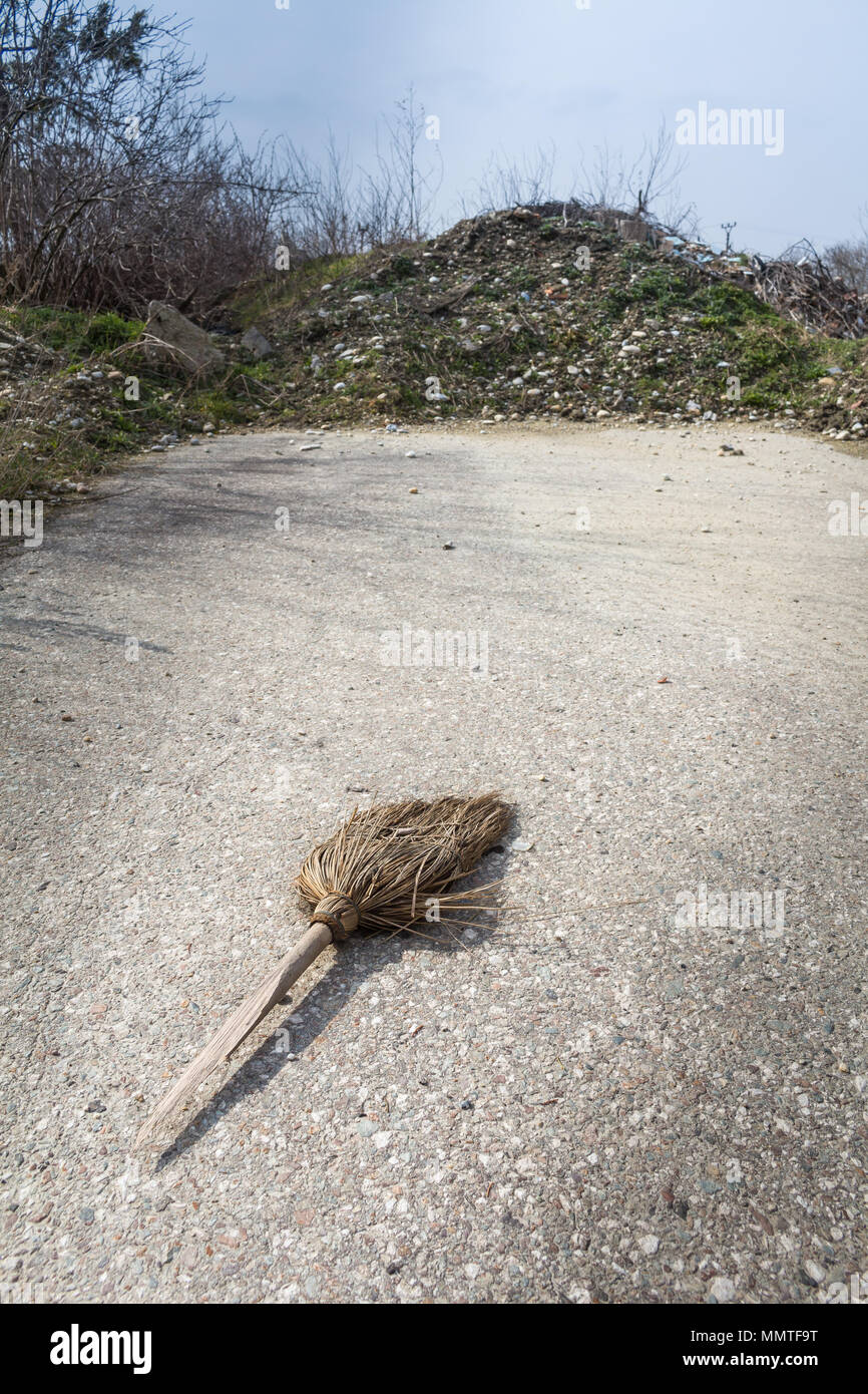 Vecchio besom su una strada asfaltata, circondato da un jukyard.pila Foto Stock