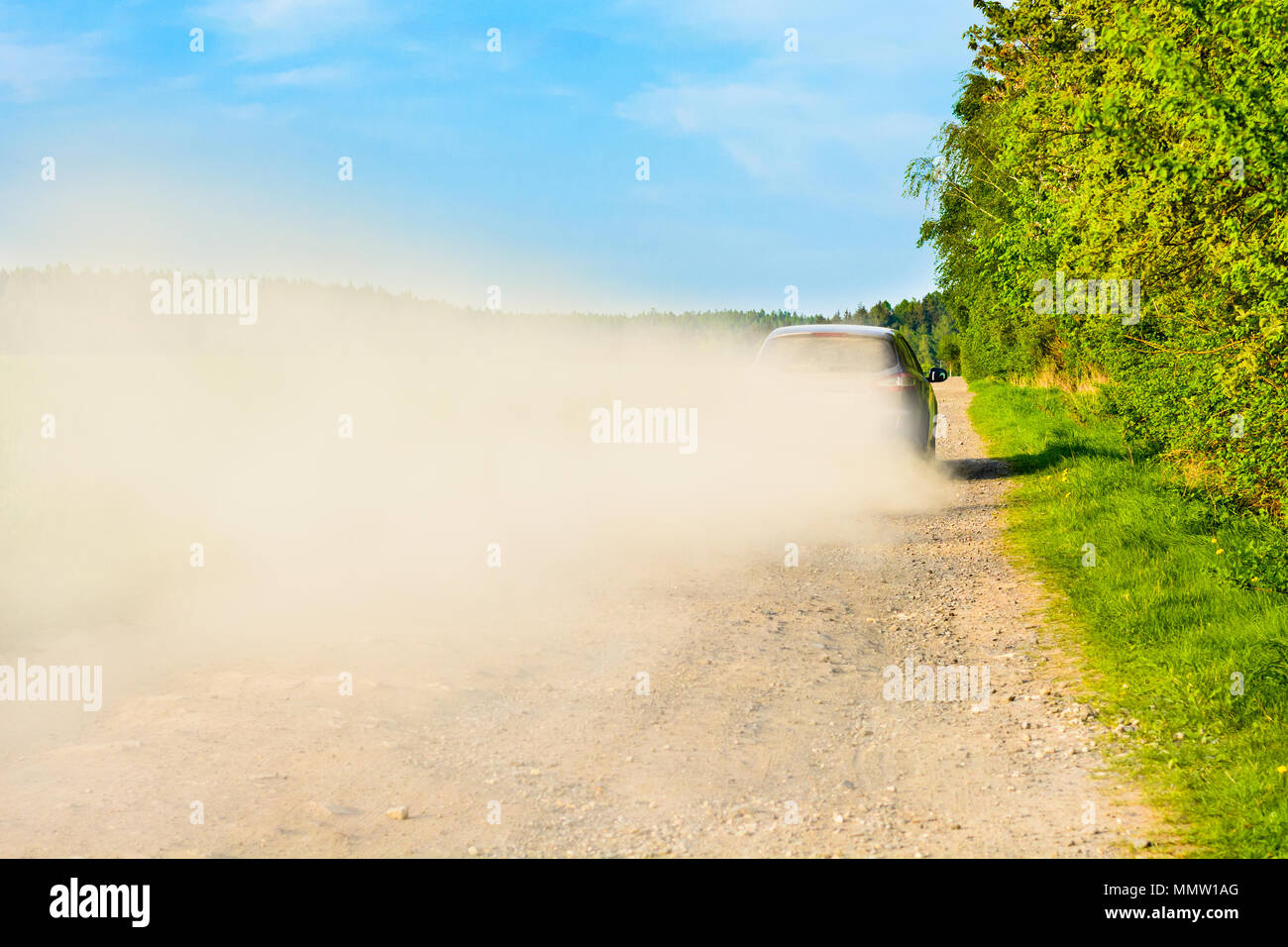 In auto su una strada polverosa in una nuvola di polvere. Una vettura su una strada di ghiaia. Un viaggio confortevole in un'autovettura. Foto Stock