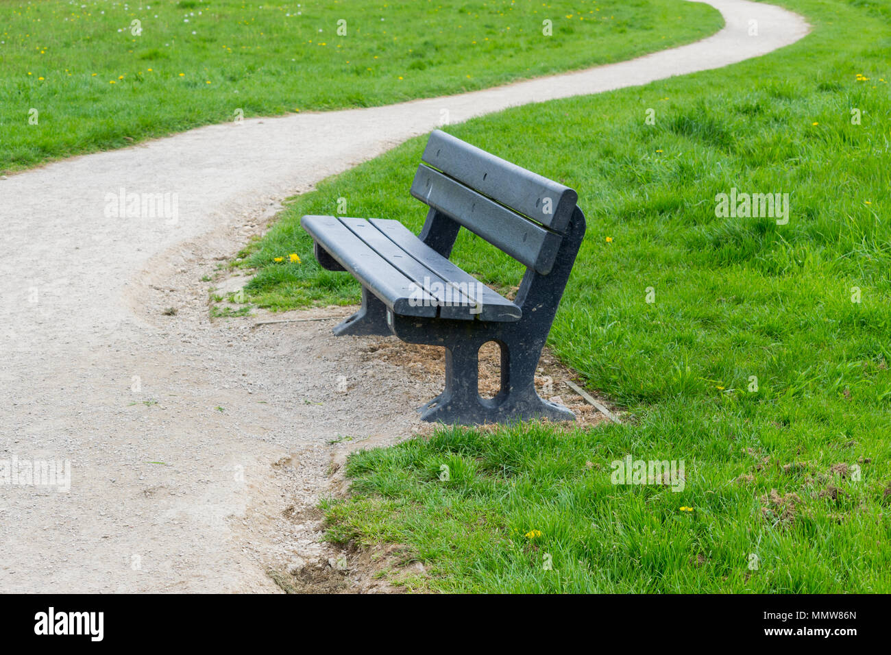 Blu di una panca in legno situato accanto a un avvolgimento percorso di ghiaia Foto Stock