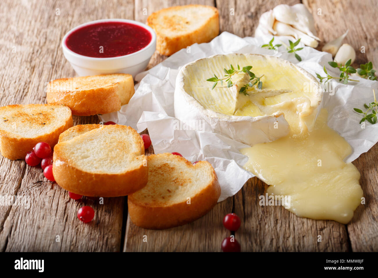 Il francese del cibo tradizionale formaggio Camembert con aglio, timo è servita con pane tostato e salsa di frutti di bosco vicino sul tavolo orizzontale. Foto Stock