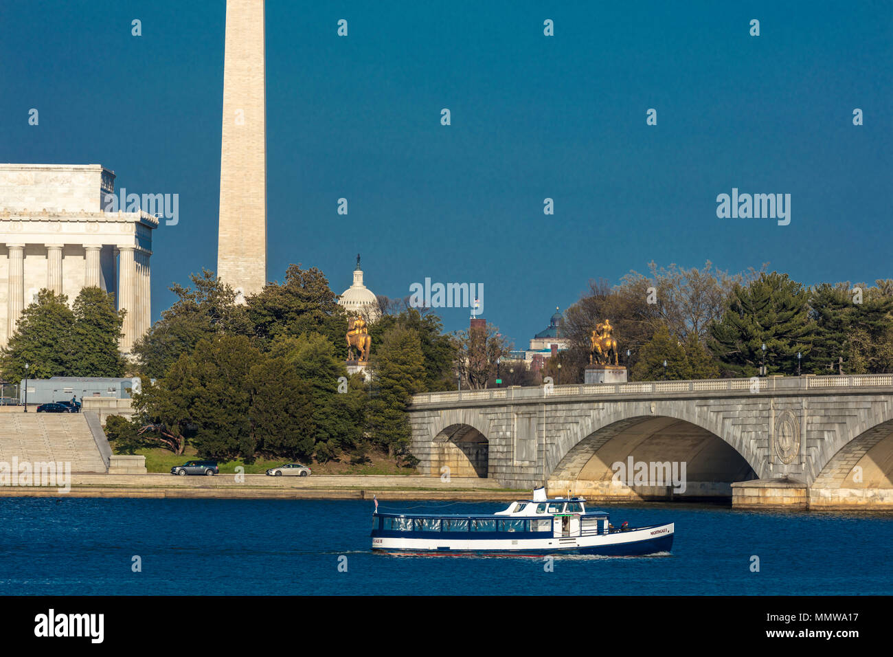 Aprile 10, 2018 - Washington D.C. - Ponte Memoriale campate Fiume Potomac e caratteristiche il Lincoln Memorial e il Monumento a Washington con il tour in barca nel telaio inferiore al tramonto Foto Stock