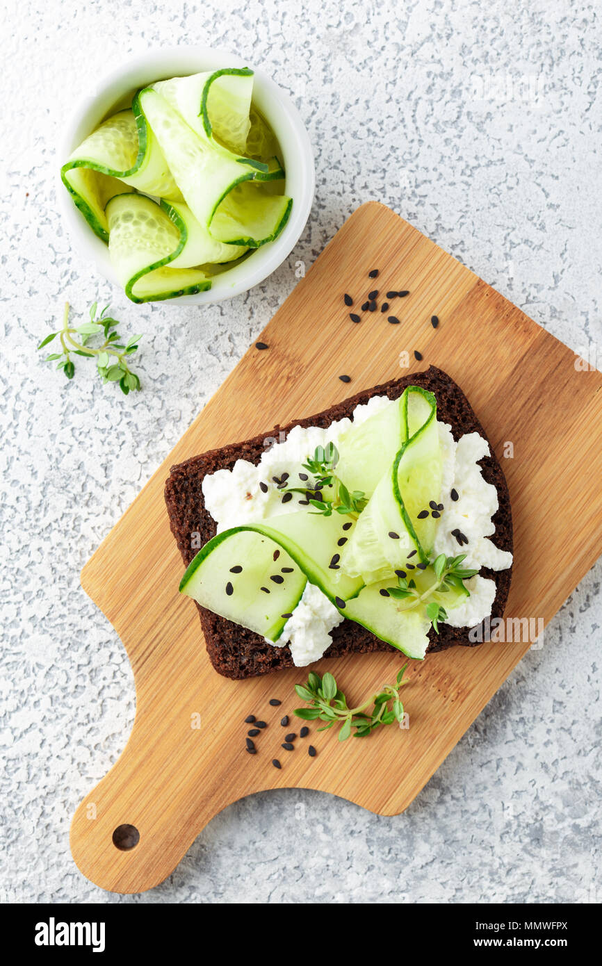 Crostini di pane di segale con ricotta, cetriolo e sesamo nero su grigio ardesia e pietra o calcestruzzo sfondo. Foto Stock