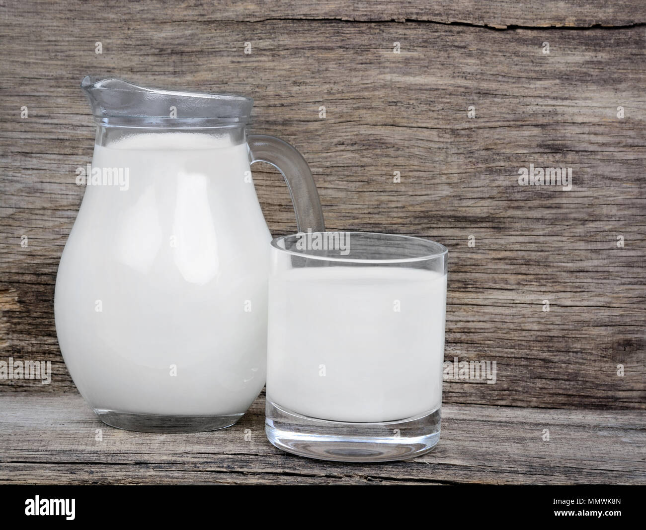 Latte in vetreria su tavola in legno rustico Foto Stock