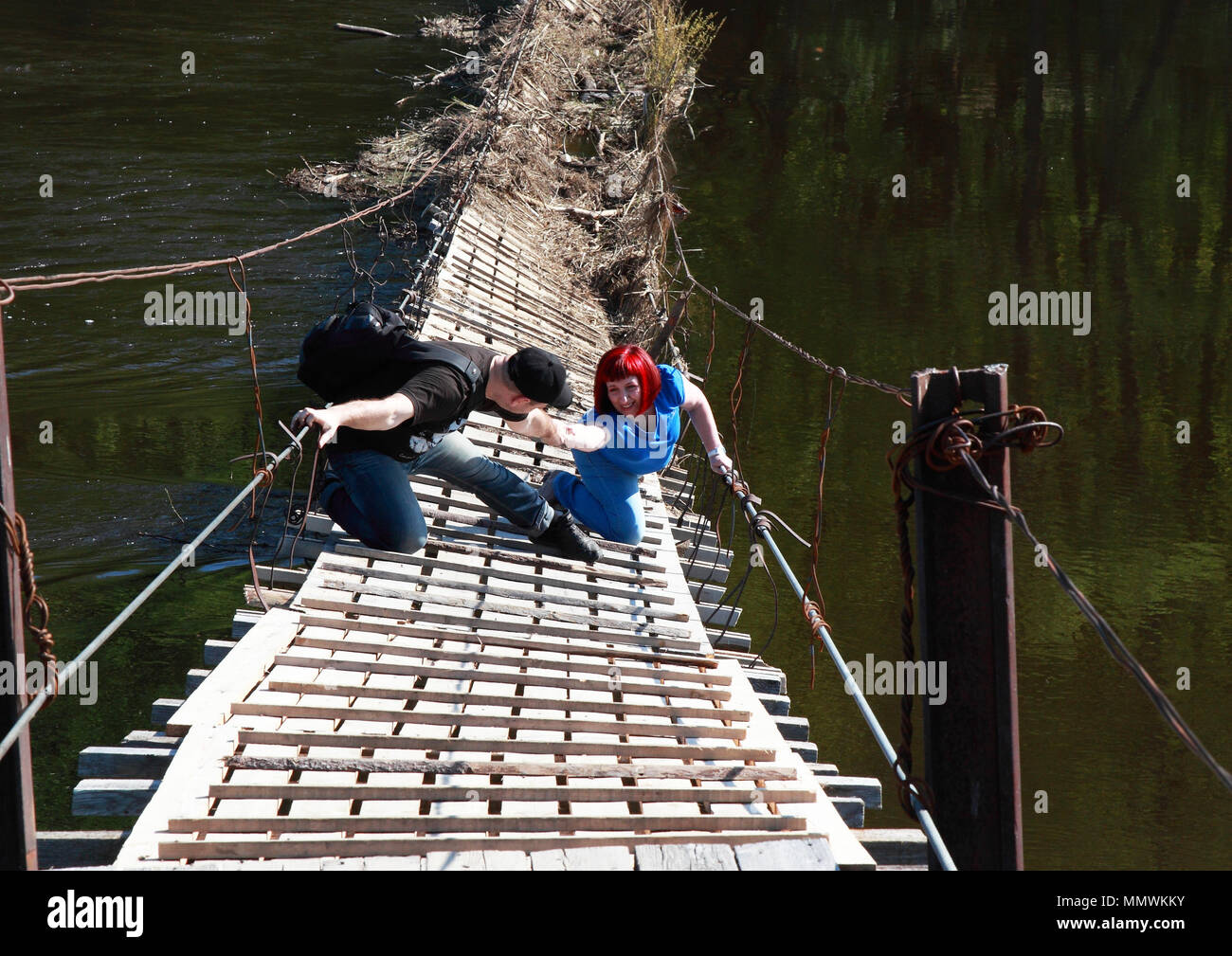 Il vecchio ponte collassa sopra il fiume. Un uomo aiuta a caduta di una donna e si estende una mano. Foto Stock