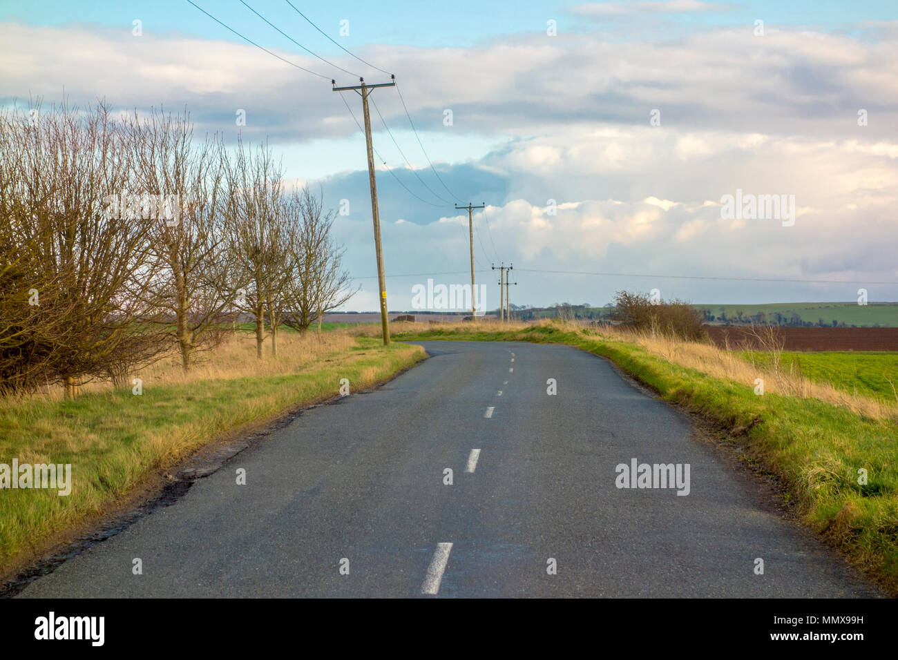 Vuoto tipico paese britannico lane, strada di campagna con pali telefonici Foto Stock