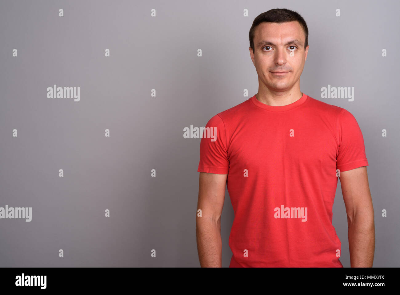 Uomo che indossa camicia rossa contro uno sfondo grigio Foto Stock