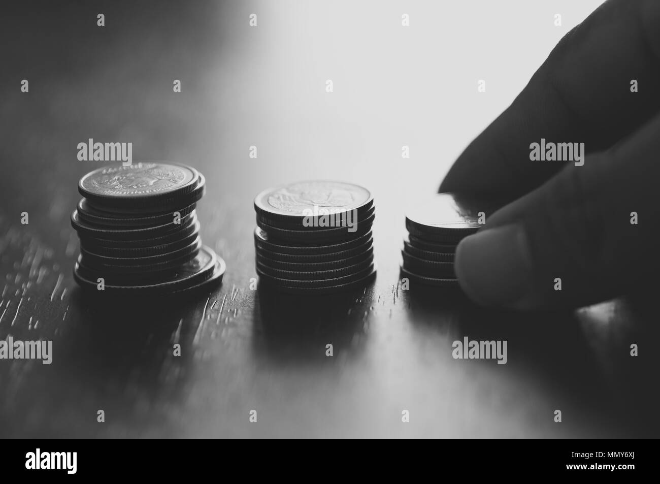Silhouette di mano mettere soldi su impilati di monete, concetto nel risparmiare denaro degli affari, della finanza, dell'economia e banca di account Foto Stock
