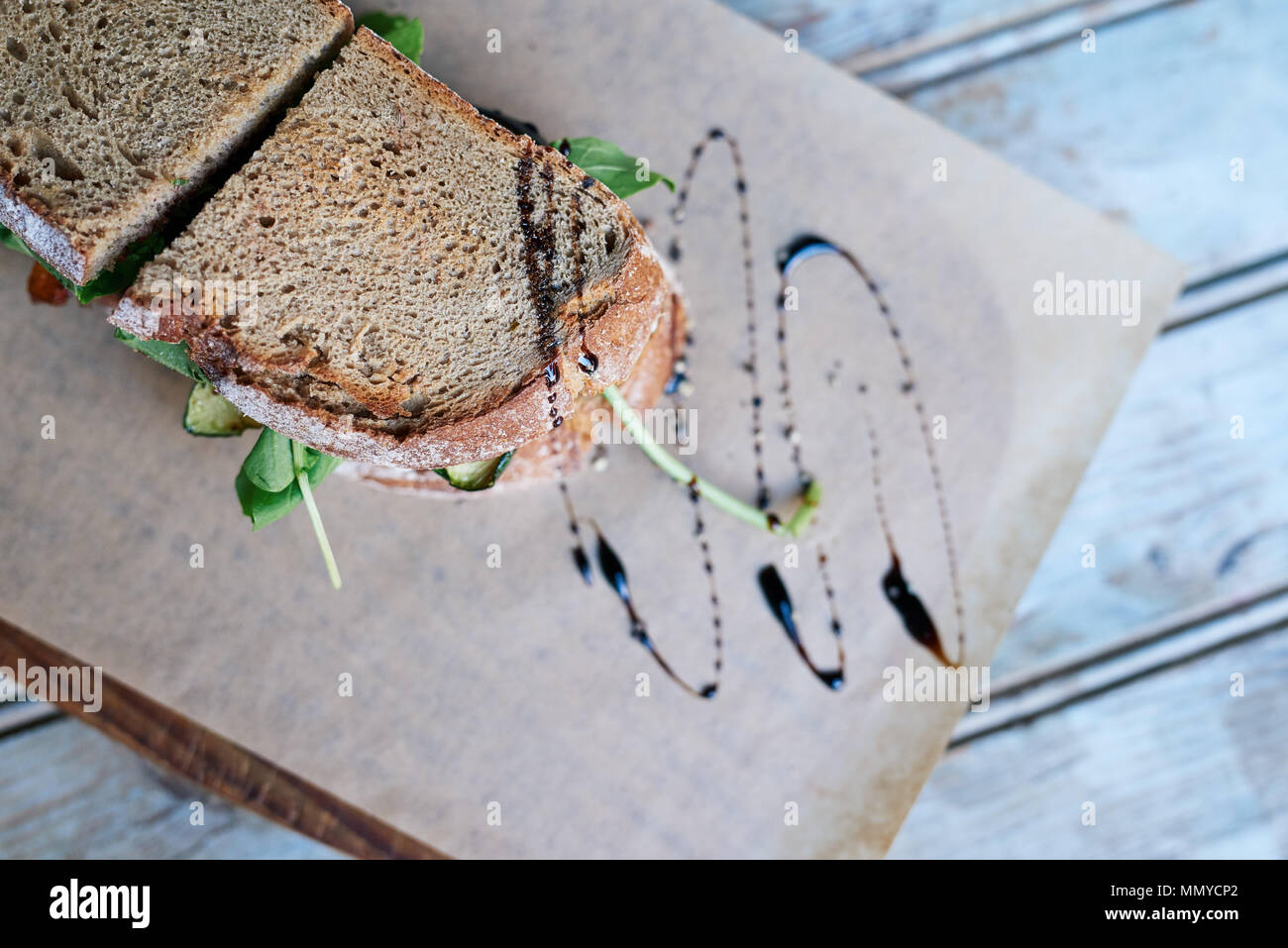 Sandwich Gourmet una spruzzata di aceto balsalmic su un tavolo di legno Foto Stock