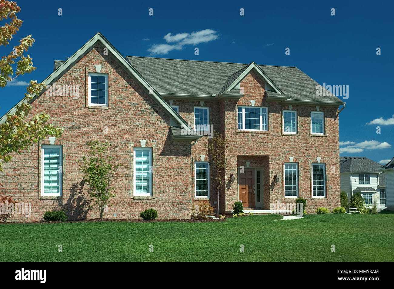 Grande casa di mattoni con un lussureggiante prato verde e un bel cielo azzurro sfondo.Una delle molte case nella mia galleria. Foto Stock