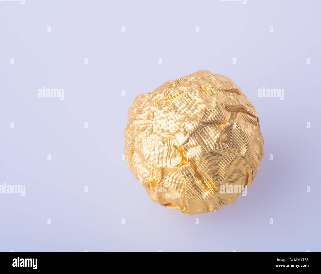 Il cioccolato a sfera o sfera di cioccolato con mandorle in oro una carta stagnola sullo sfondo Foto Stock