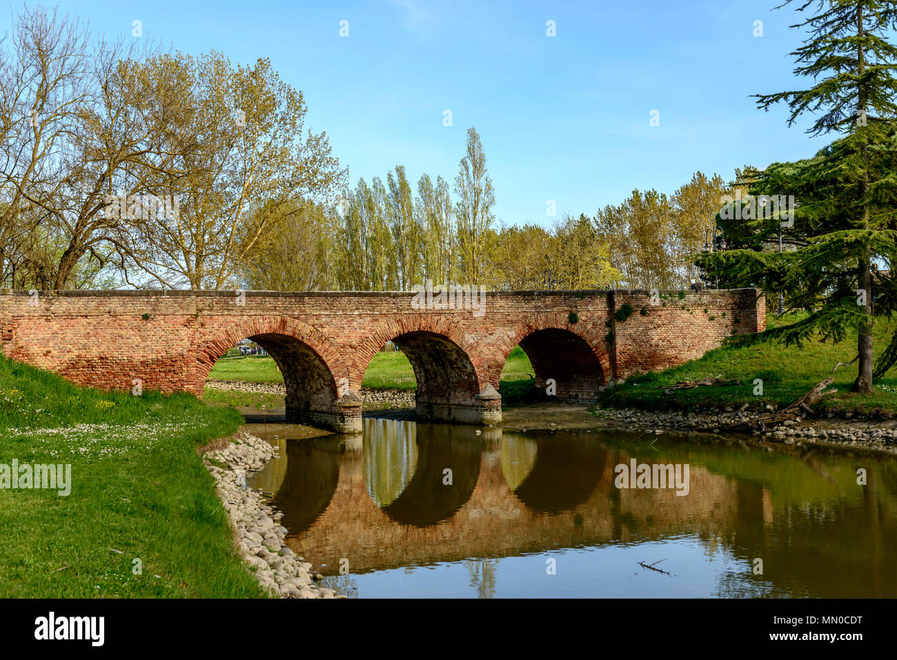Vista del vecchio ponte di mattoni a antica abbazia romanica giardini, girato in primavera luminoso della luce del sole a Pomposa, Ferrara, Italia Foto Stock