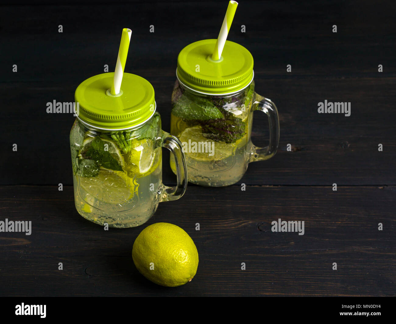 Cocktail Mojito con fettine di lime e menta in un recipiente su legno scuro dello sfondo. Estate bevanda analcolica Foto Stock