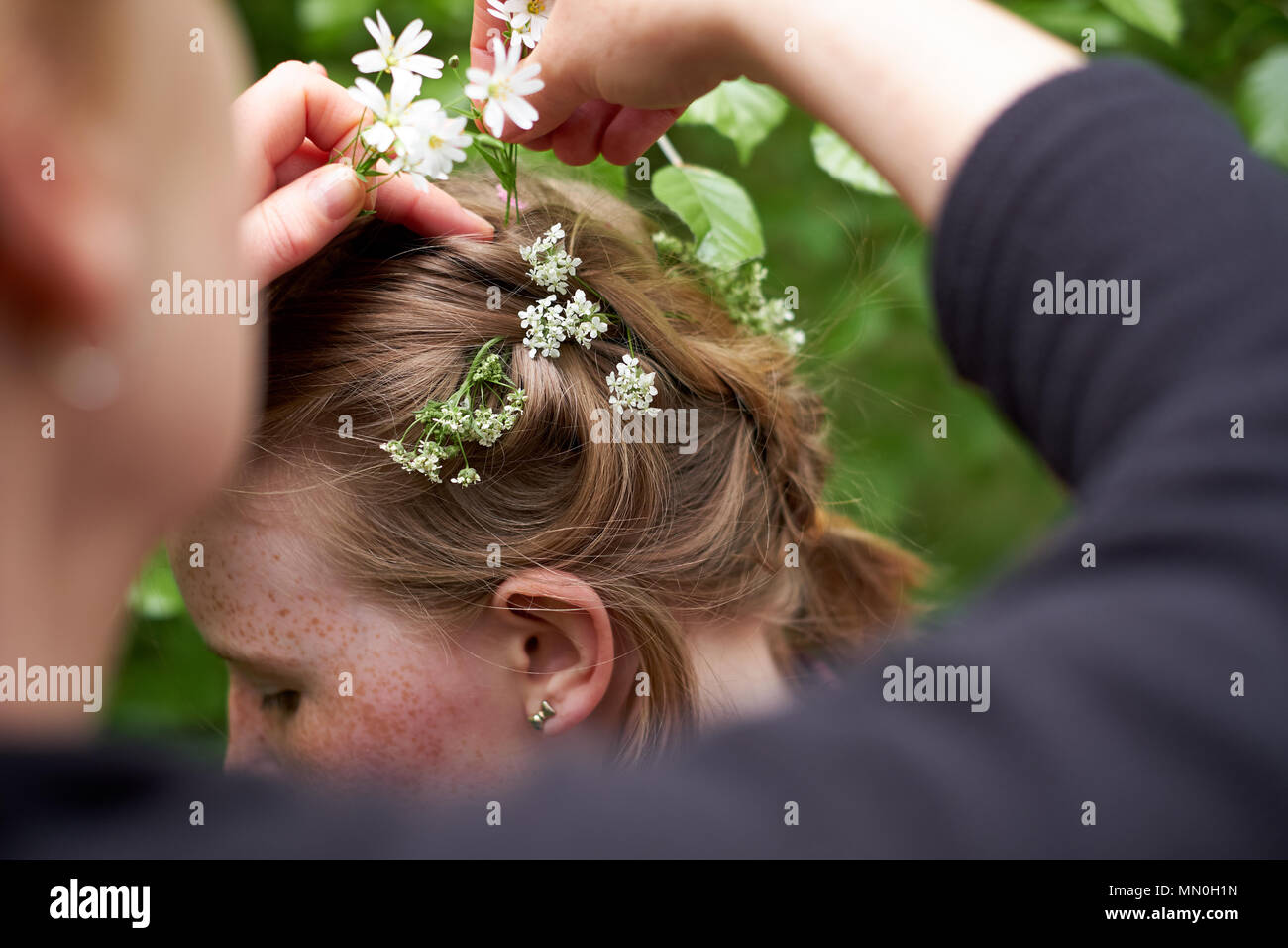 Una giovane ragazza ha fiori di primavera collocato nel suo capelli intrecciati Foto Stock