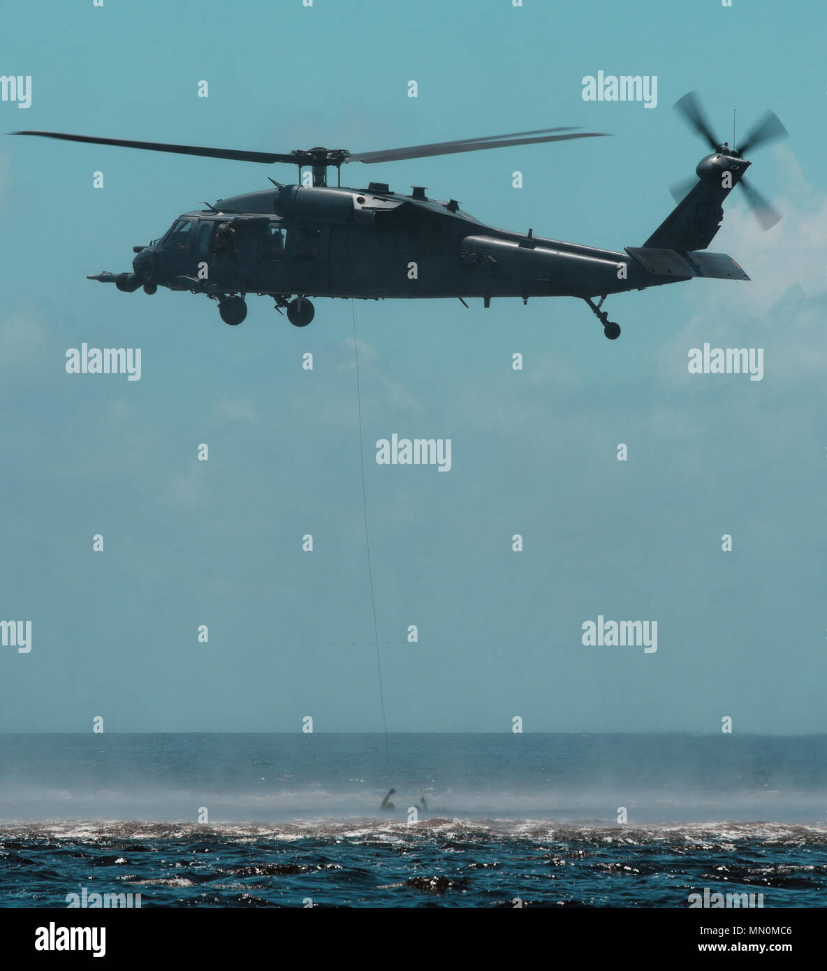 Un U.S. Air Force HH-60 Pave Hawk si abbassa di un cavo nell'acqua durante un salvataggio dell'acqua esercizio di Carrabelle Fla., Agosto 7, 2017. Avieri da entrambi Tyndall Air Force Base e Moody Air Force Base ha preso parte in esercizio custode Stealth con l'obiettivo di aumentare la loro disponibilità ed esperienza. (U.S. Air Force Foto di Airman 1. Classe Tybee Hurst/rilasciato) Foto Stock