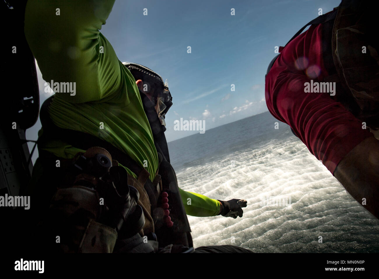 Il personale Sgt. Robert, 38th Rescue Squadron pararescueman, dirige un compagno di PJ per tuffarsi in acqua, 7 Agosto, 2017, vicino all isola di cane, Fla. aviatori dal 23d Ala e 325Fighter Wing condotte di acqua durante il giorno le operazioni di soccorso di formazione in collaborazione con l'esercizio Stealth Guardian, che è progettata per testare il personale di volo con il mondo reale degli scenari di esercizio simile a un distribuito o ambiente di emergenza. (U.S. Air Force photo by Staff Sgt. Ryan Callaghan) Foto Stock