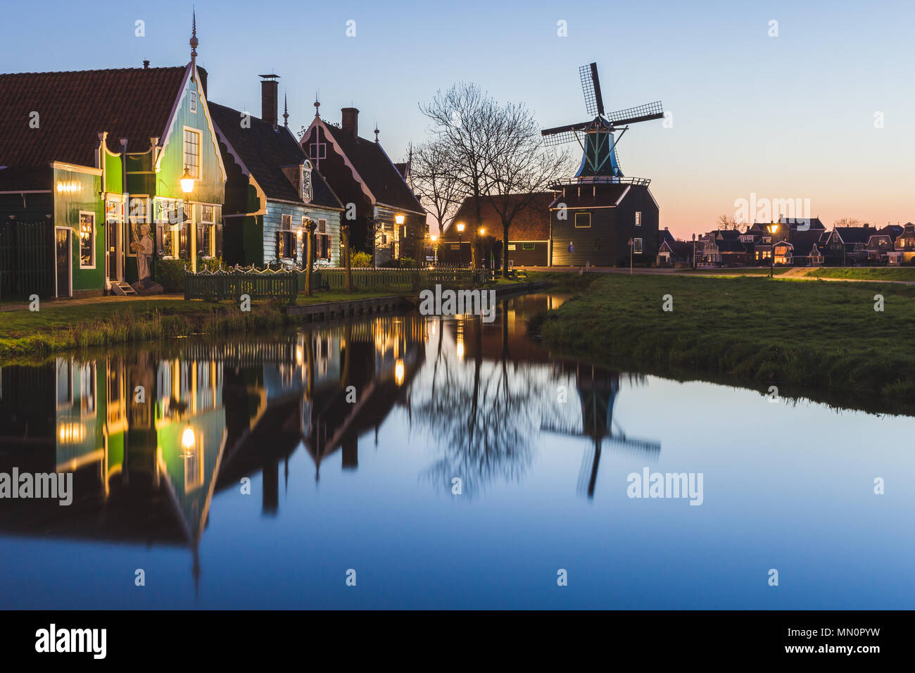 Case in legno e il mulino a vento sono riflesse nelle acque blu del fiume Zaan Zaanse Schans Olanda settentrionale dei Paesi Bassi in Europa Foto Stock