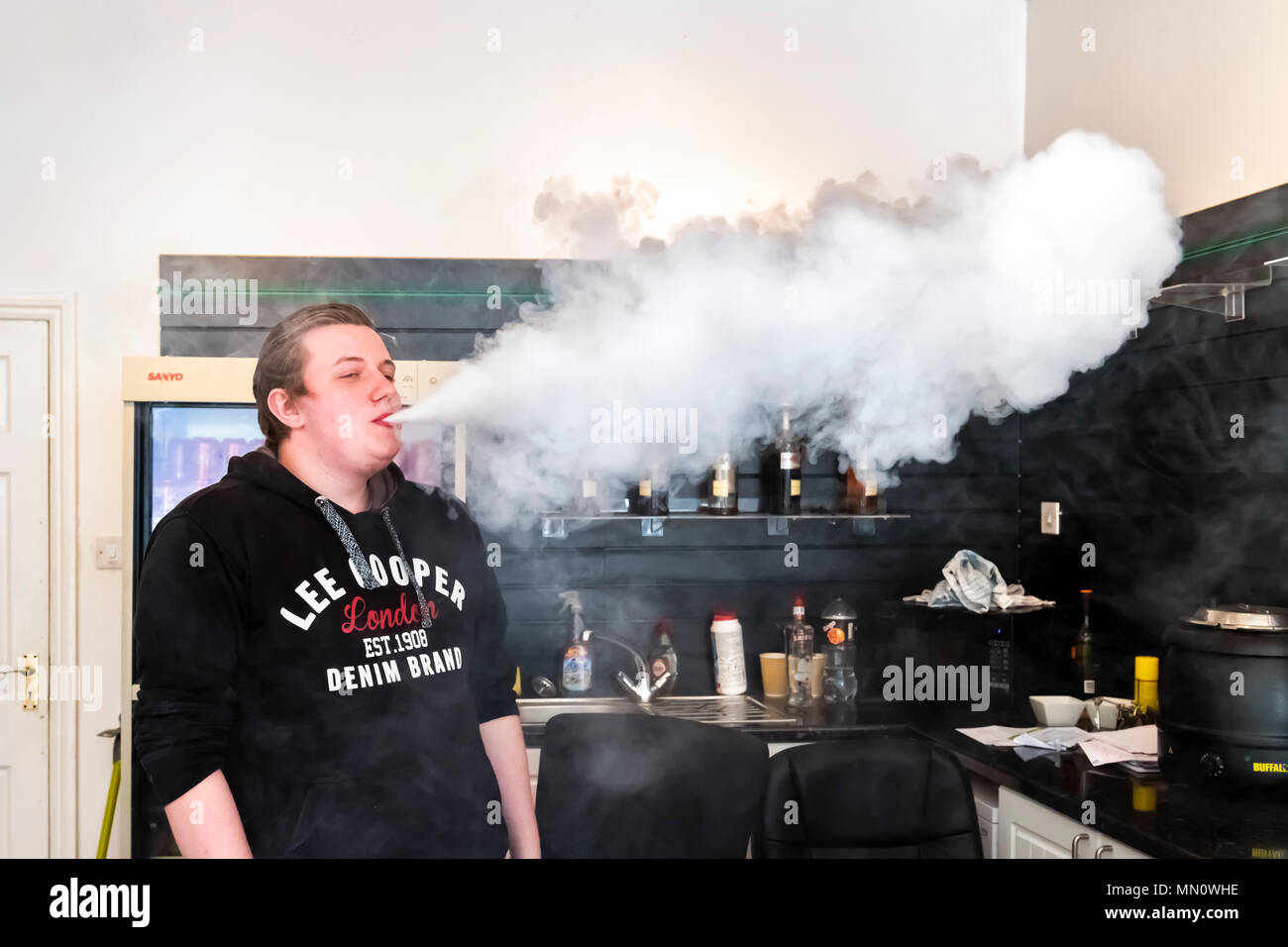 Giovane uomo dimostrando vaping all'interno di un negozio vaping Foto Stock