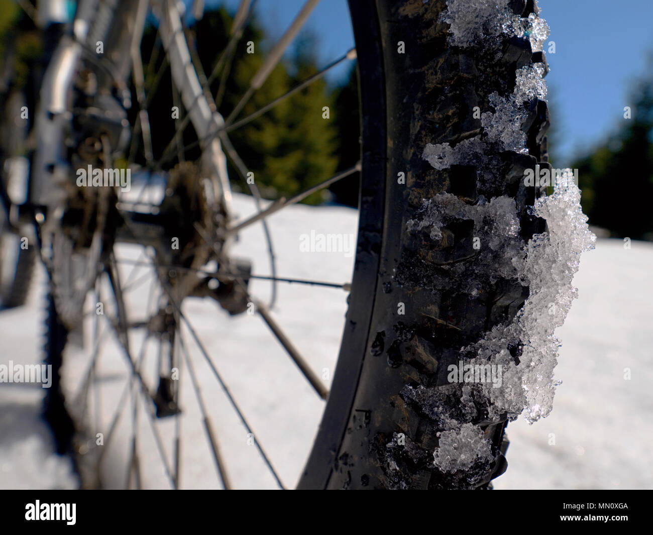 Mountain bike soggiorno a neve, sharp sole nel cielo blu. In inverno lo sfruttamento di bicicletta in montagna Foto Stock