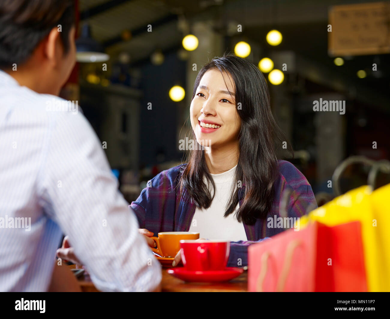 Giovani asiatici gli amanti della coppia seduta a tavola in chat parlando in coffee shop dopo lo shopping. Foto Stock