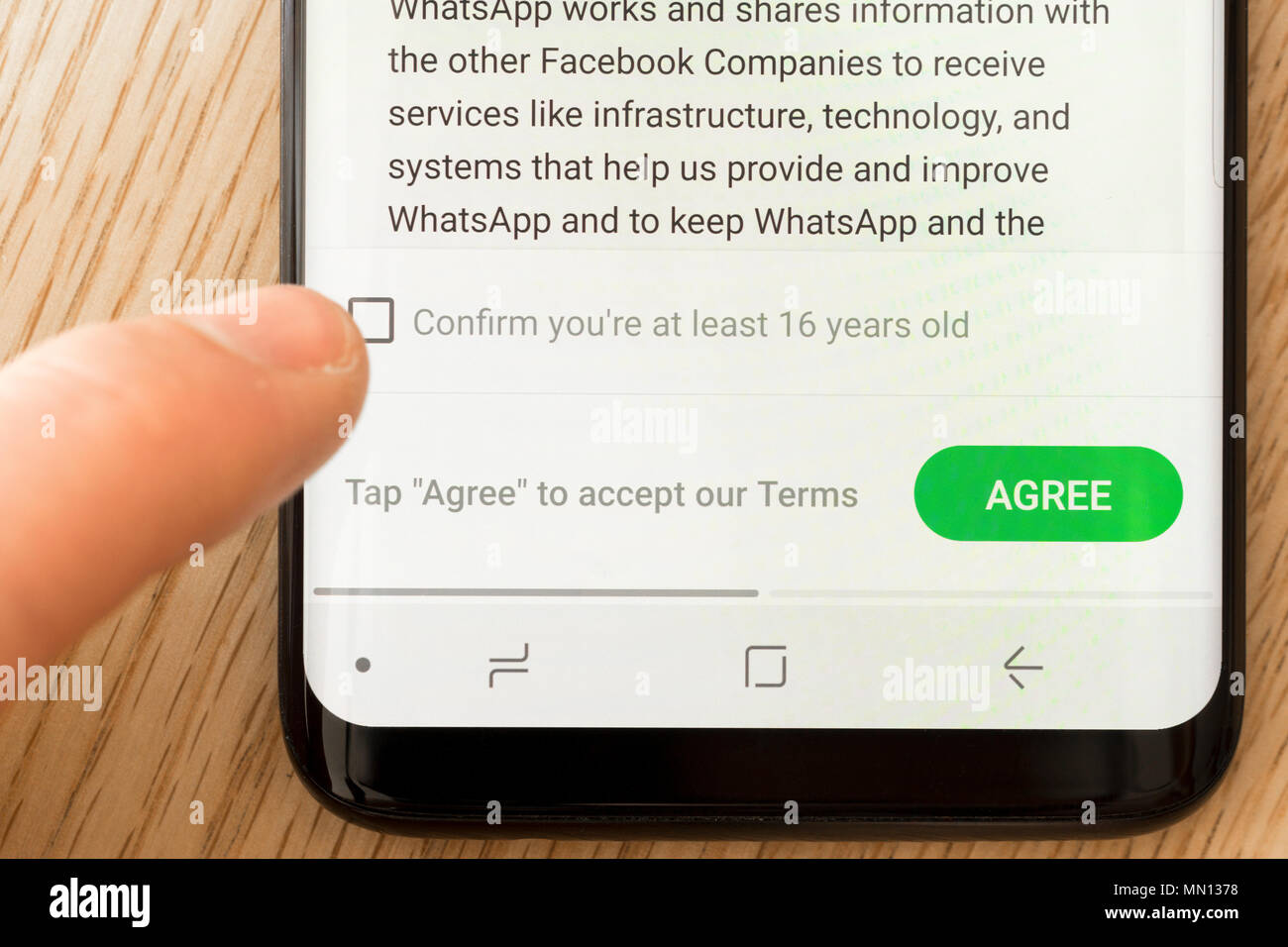 Un uomo che conferma la sua età sui termini e la Politica sulla Privacy pagina del Whatsapp app su uno smartphone Foto Stock