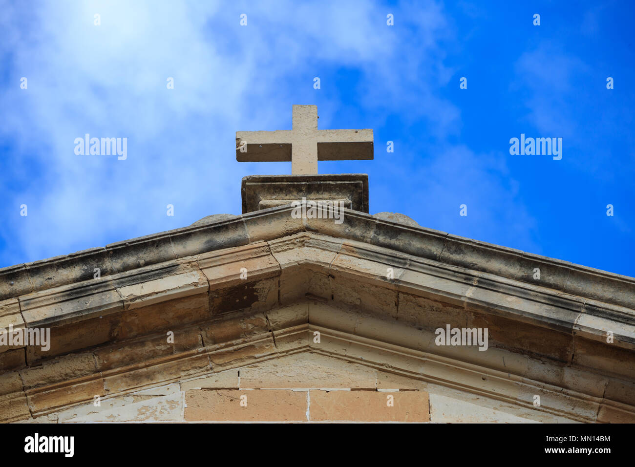 San Giovanni Battista cappella in Malta. Croce bianca sulla parte superiore di un edificio di pietra calcarea. Cielo blu con nuvole di sfondo. Meta religiosa. Foto Stock