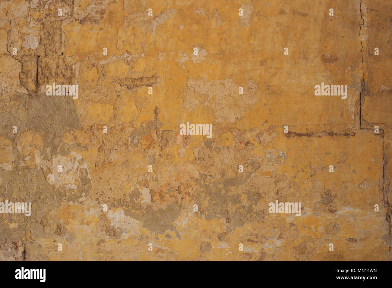 Weathered dipinte di un giallo sullo sfondo della parete, parzialmente sbiadito. Corroso, sbucciate, vintage, muro grezzo per sfondo. Vista ravvicinata con i dettagli. Foto Stock