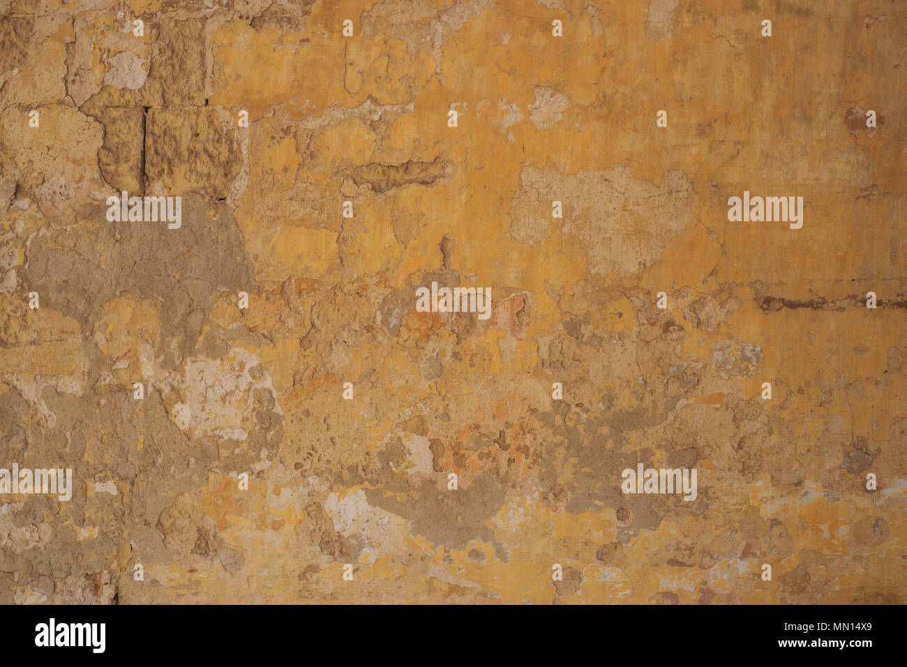 Weathered dipinte di un giallo sullo sfondo della parete, parzialmente sbiadito. Corroso, sbucciate, vintage, muro grezzo per sfondo. Vista ravvicinata con i dettagli. Foto Stock