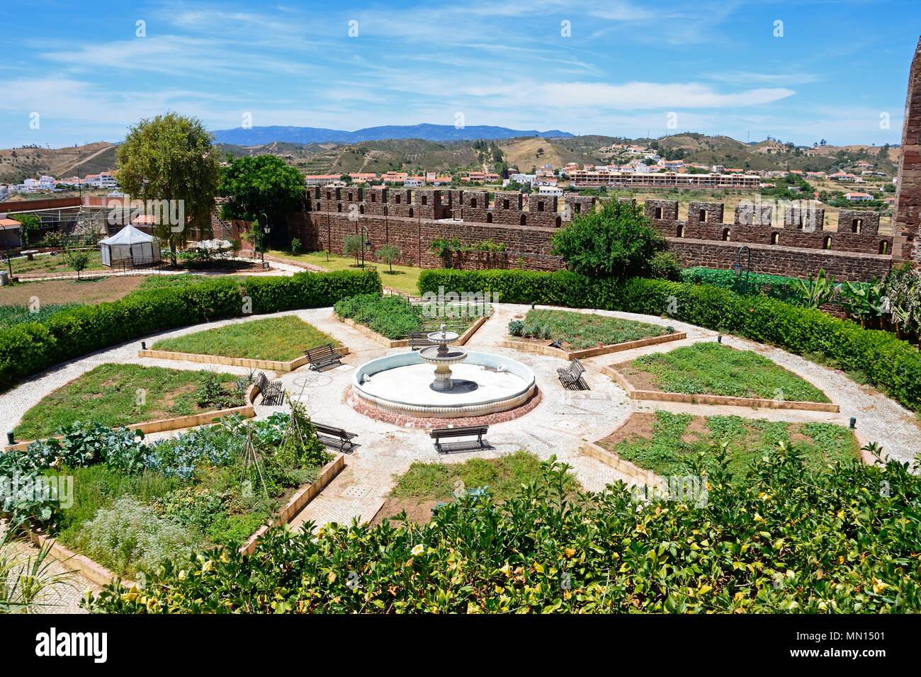 Giardini botanici con una fontana al centro all'interno del castello medievale con merlature alla parte posteriore, Silves, del Portogallo, dell'Europa. Foto Stock