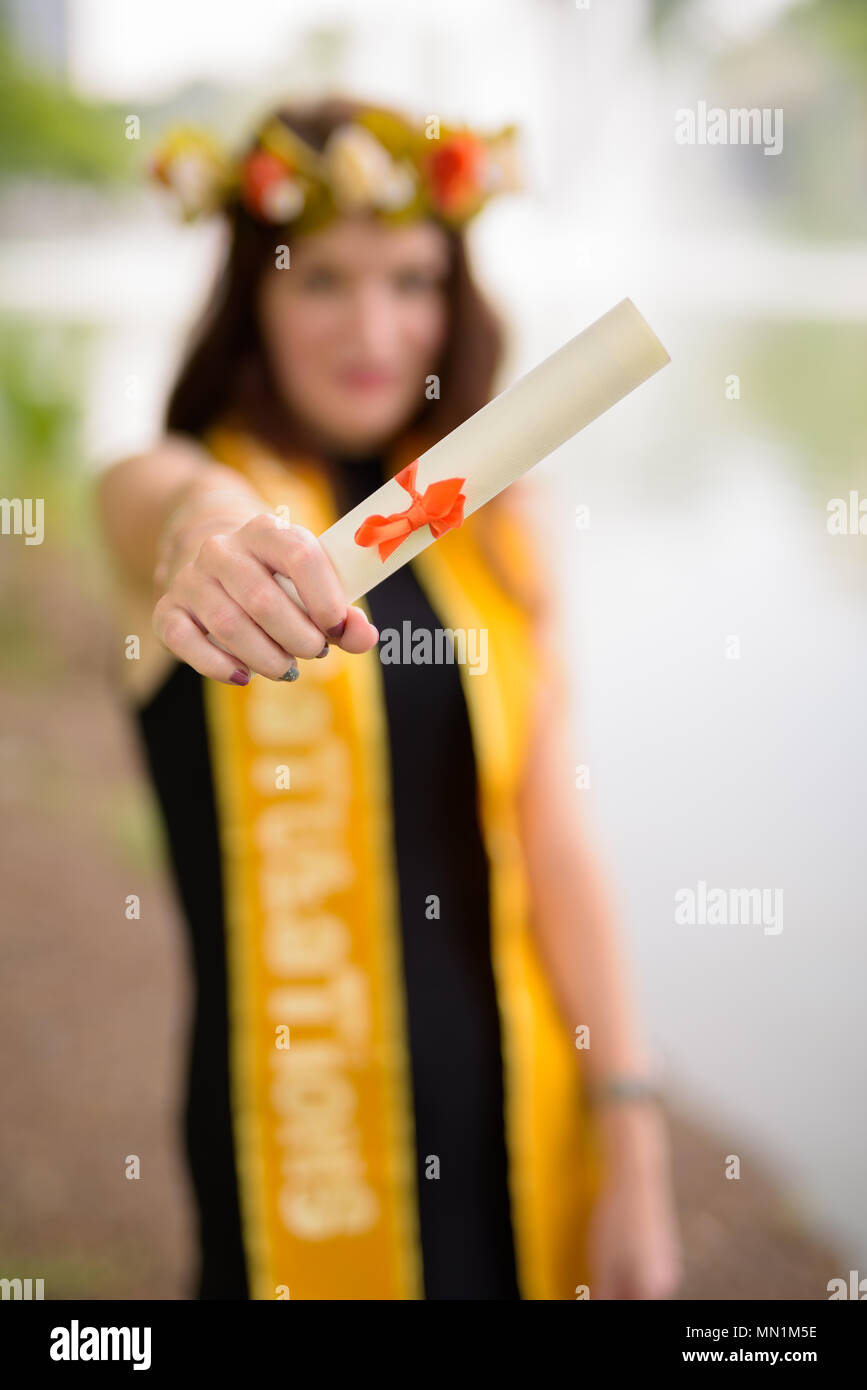 Giovane bella donna celebrando la laurea presso il parco in Bang Foto Stock