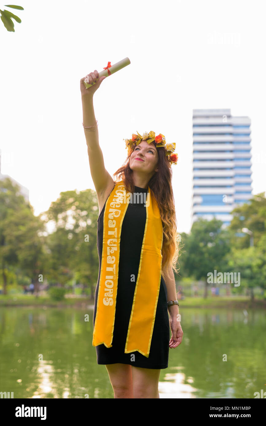 Giovane bella donna celebrando la laurea presso il parco in Bang Foto Stock
