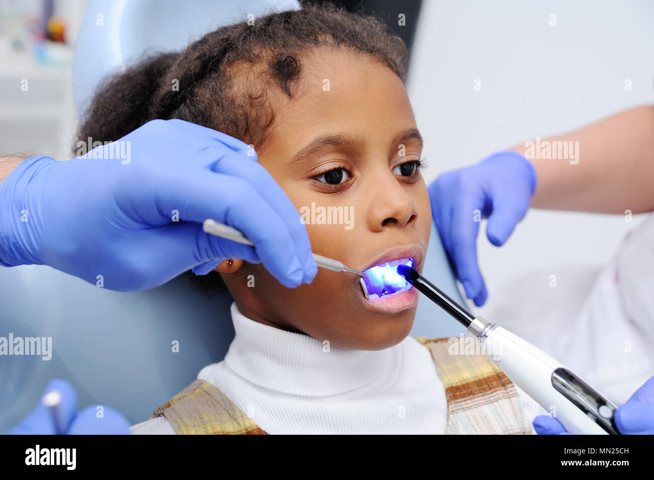 Una di carnagione scura bambina sulla poltrona del dentista Foto Stock