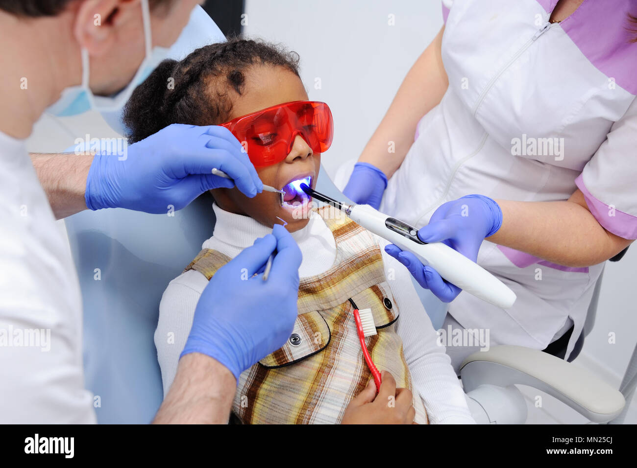 Una di carnagione scura bambina sulla poltrona del dentista Foto Stock