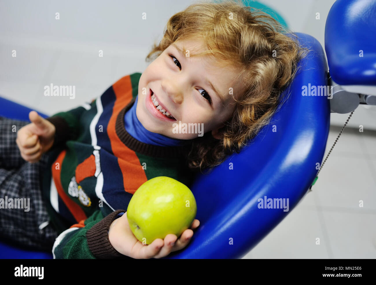 Curly-pelose baby boy in poltrona odontoiatrica Foto Stock