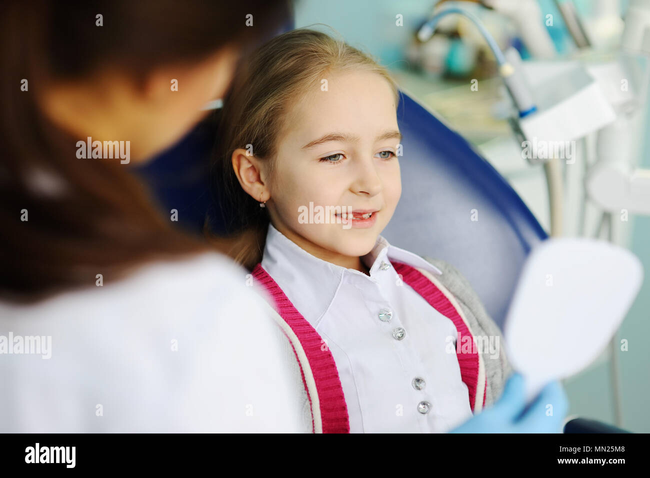 Baby girl esamina i denti in un specchio dentale Foto Stock