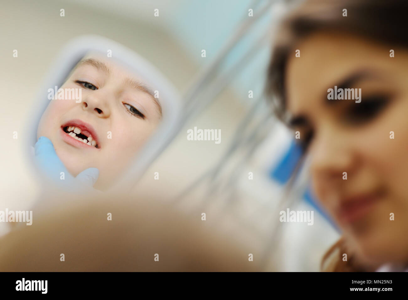 Ragazza esamina i denti in un specchio dentale Foto Stock