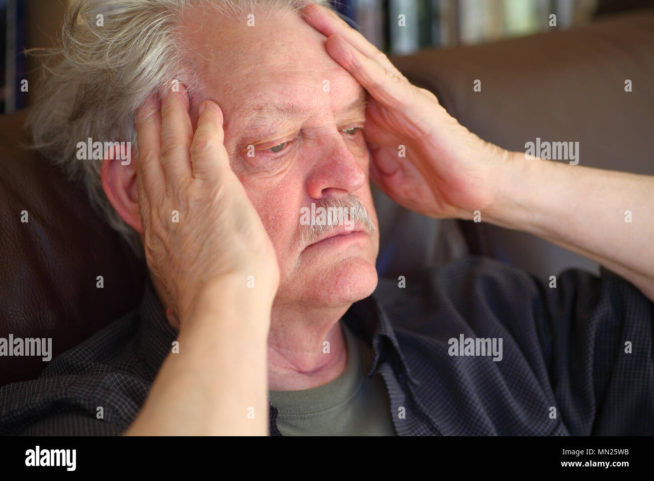 Senior uomo seduto con un grande mal di testa Foto Stock