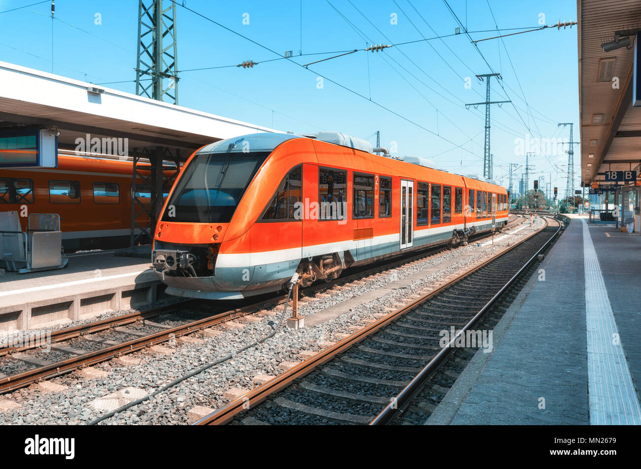 Alta velocità trenino rosso sulla stazione ferroviaria al tramonto. Norimberga, Germania. Moderno treno intercity sulla linea ferroviaria piattaforma. Industriali. Treni pendolari Foto Stock