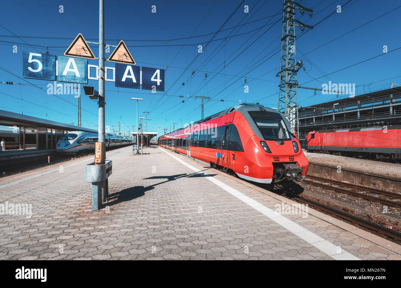 Alta velocità trenino rosso sulla stazione ferroviaria al tramonto. Norimberga, Germania. Moderno treno intercity sulla linea ferroviaria piattaforma. Industriali. Treni pendolari Foto Stock