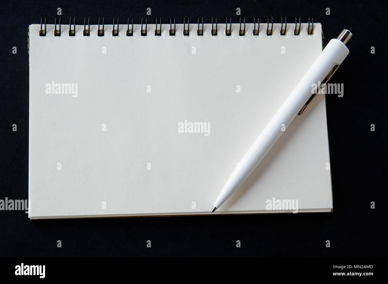 Penna e notebook in bianco su sfondo nero Foto Stock