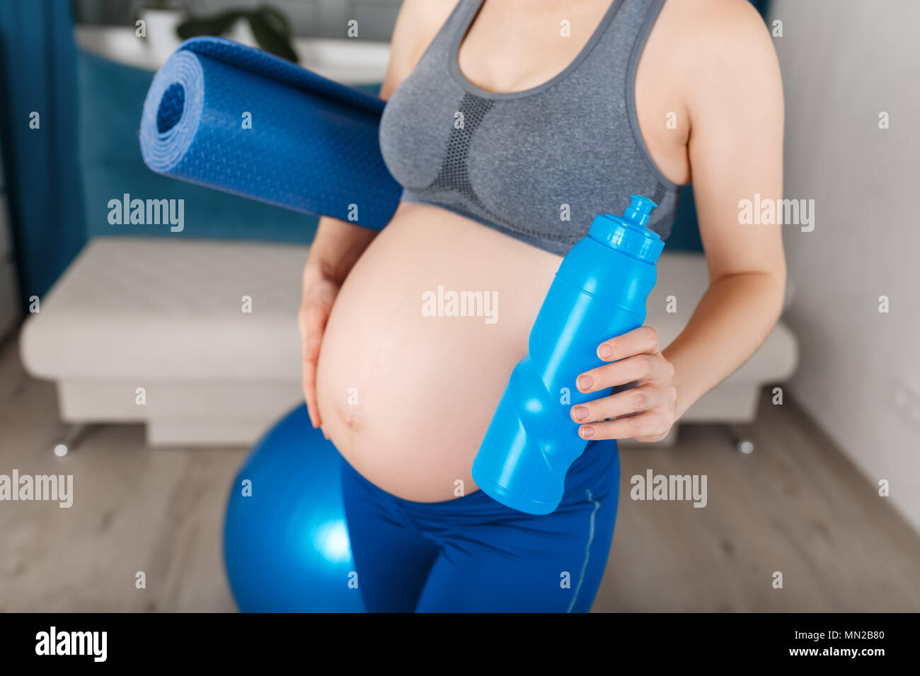 Donna incinta con materassino yoga e una bottiglia di acqua Foto Stock
