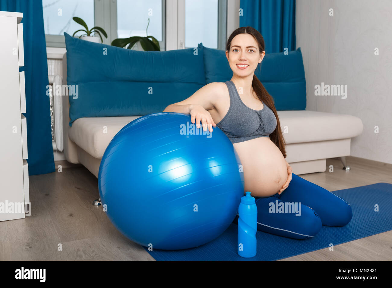 Donna incinta con montare la sfera a casa Foto Stock