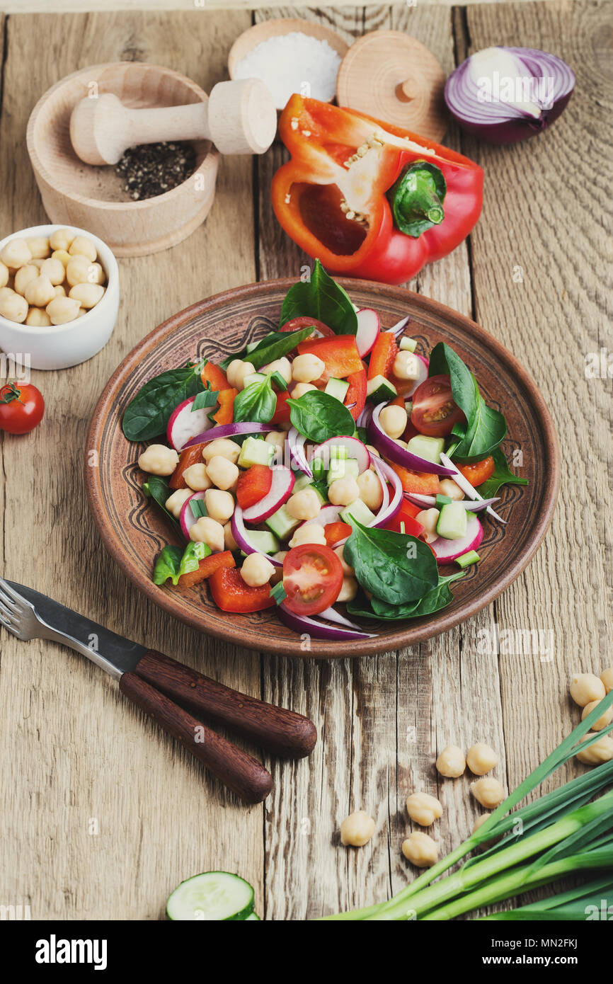 Chickpears e verdura fresca insalata in vaso di ceramica, sano pasto vegano su tavola in legno rustico Foto Stock