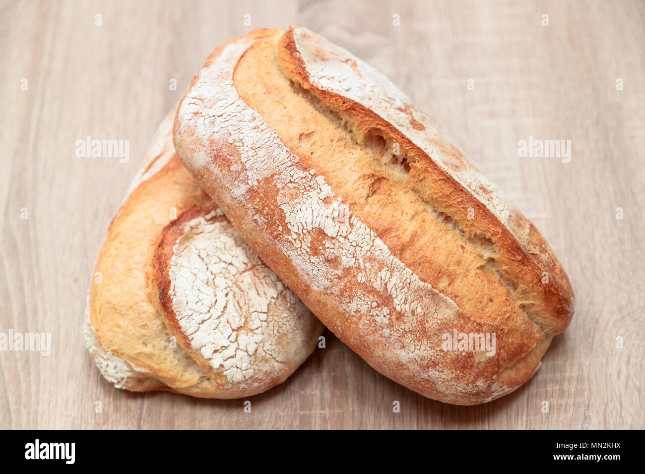 Due gustoso pane cotto su una luce sullo sfondo di legno Foto Stock