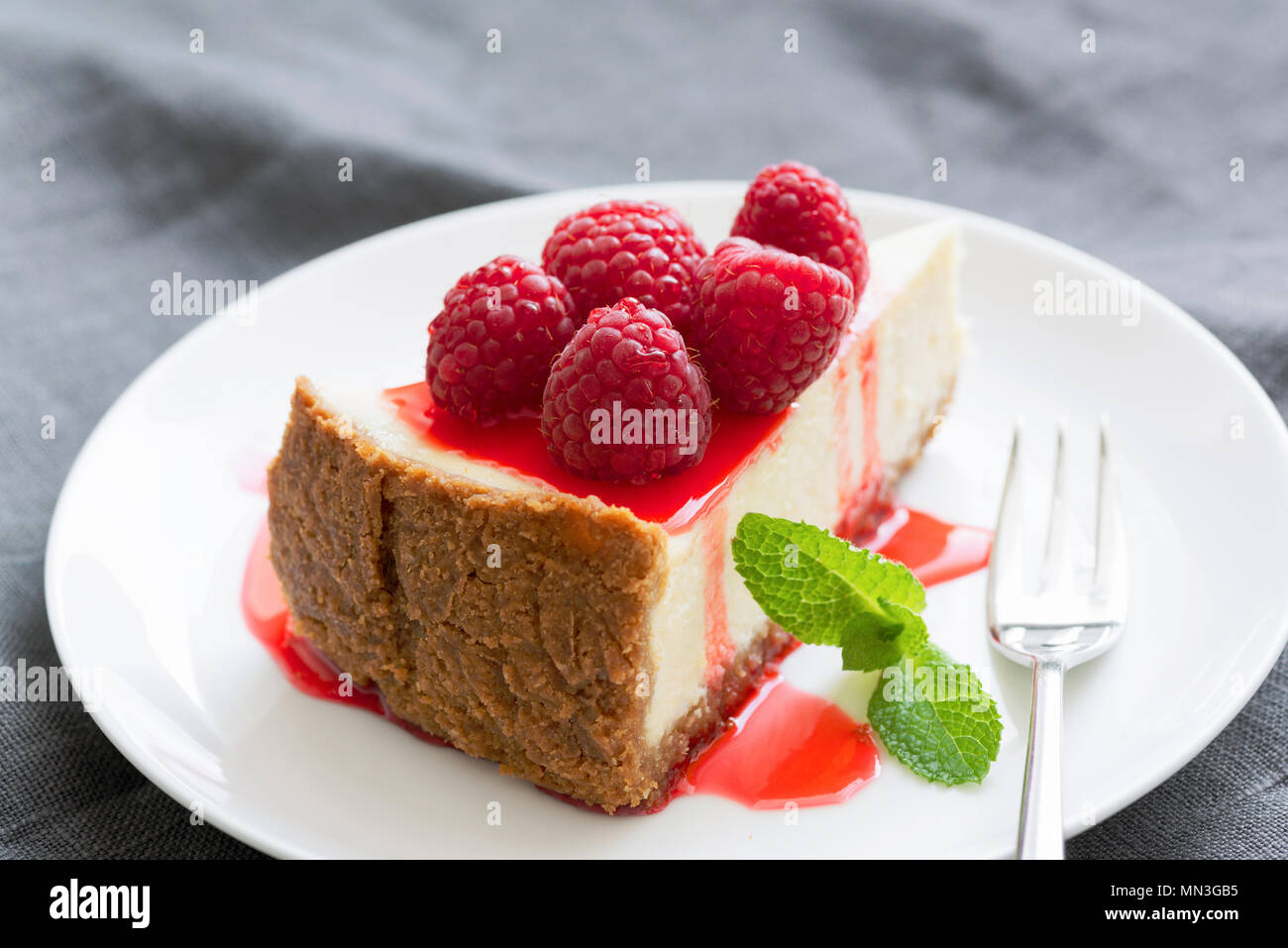 Cheesecake con salsa di frutti di bosco e lamponi freschi sulla piastra bianca. Messa a fuoco selettiva, composizione orizzontale Foto Stock